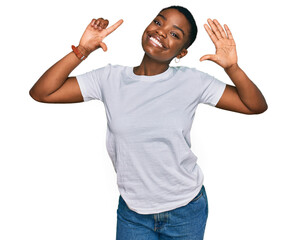 Young african american woman wearing casual white t shirt showing and pointing up with fingers number seven while smiling confident and happy.