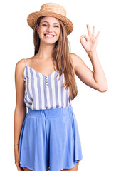 Obraz na płótnie Canvas Young beautiful blonde woman wearing summer hat smiling positive doing ok sign with hand and fingers. successful expression.