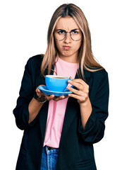 Hispanic young woman drinking a cup of coffee skeptic and nervous, frowning upset because of problem. negative person.