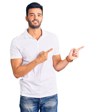 Young handsome hispanic man wearing casual clothes pointing aside worried and nervous with both hands, concerned and surprised expression