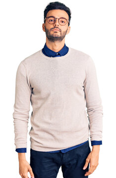 Young handsome hispanic man wearing elegant clothes and glasses relaxed with serious expression on face. simple and natural looking at the camera.