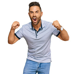 Fototapeta premium Handsome man with beard wearing casual clothes angry and mad raising fists frustrated and furious while shouting with anger. rage and aggressive concept.