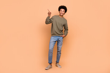 Full body length photo of young man wear trendy outfit advertise indicate finger empty space new zara sale isolated on beige color background