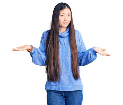 Young beautiful chinese woman wearing casual turtleneck sweater clueless and confused expression with arms and hands raised. doubt concept.