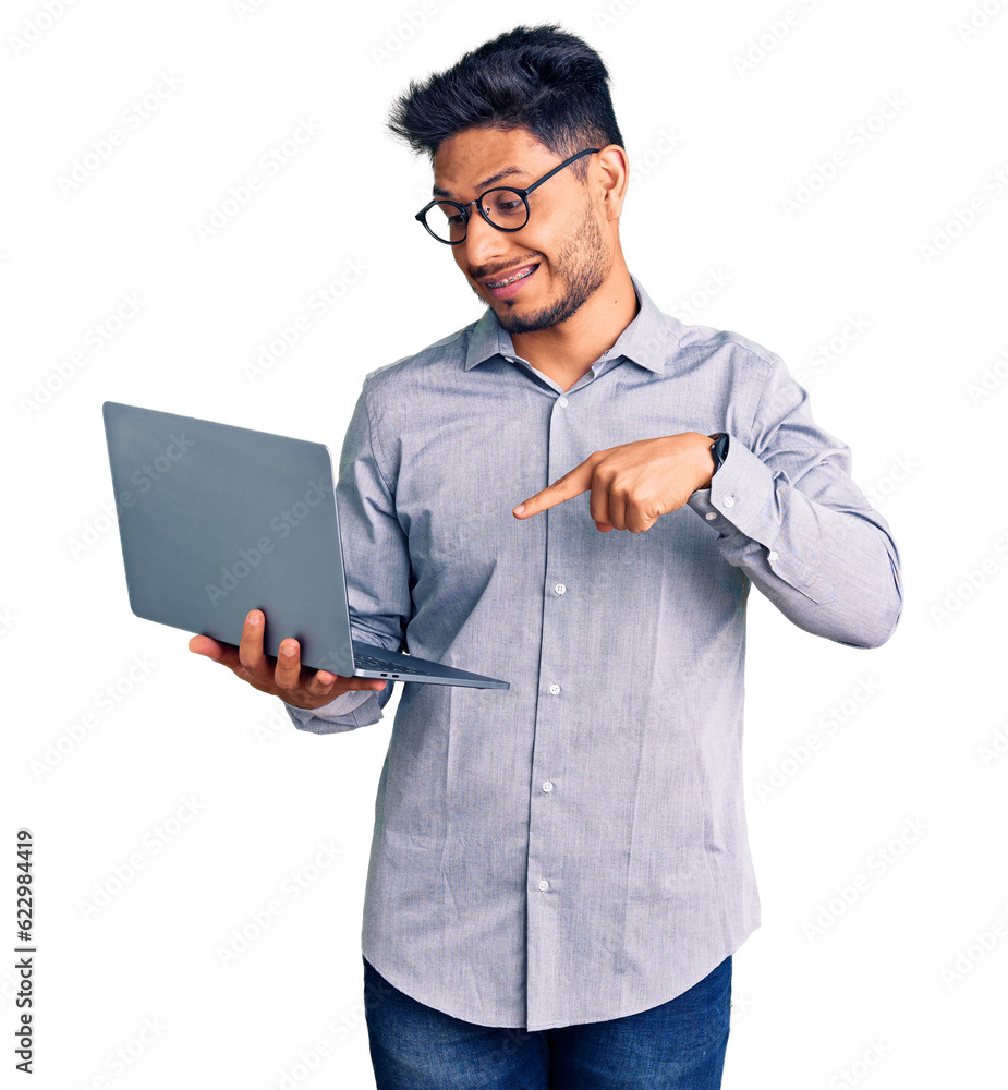 Wall mural Handsome latin american young man working using computer laptop smiling happy pointing with hand and finger