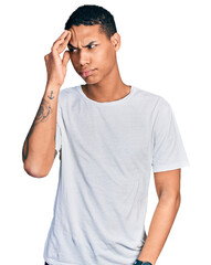 Young hispanic man wearing casual white t shirt worried and stressed about a problem with hand on forehead, nervous and anxious for crisis