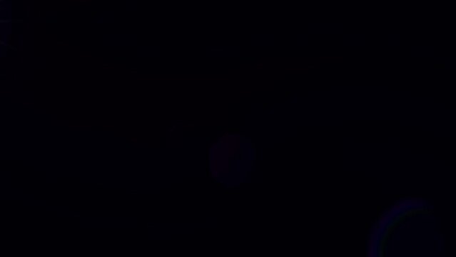 Iridescent lens flare texture on black background. Glowing green moving shape of star. Shiny rays of light in darkness. Flash in night sky. Abstract space animated backdrop. Galaxy concept. Dark cover