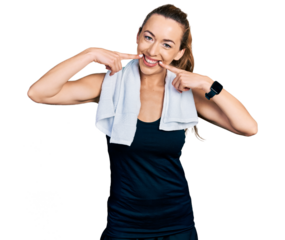 Young caucasian woman wearing sportswear and towel smiling cheerful showing and pointing with fingers teeth and mouth. dental health concept.
