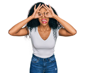 Middle age african american woman wearing casual white t shirt doing ok gesture like binoculars sticking tongue out, eyes looking through fingers. crazy expression.