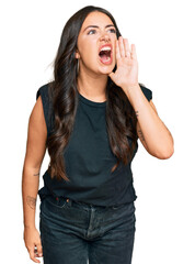 Fototapeta premium Beautiful brunette young woman wearing black shirt shouting and screaming loud to side with hand on mouth. communication concept.
