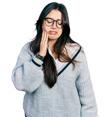 Beautiful hispanic woman wearing casual sweater and glasses touching mouth with hand with painful expression because of toothache or dental illness on teeth. dentist