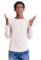 Fototapeta premium African handsome man wearing casual winter sweater celebrating mad and crazy for success with arms raised and closed eyes screaming excited. winner concept