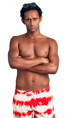 Fototapeta premium African handsome man wearing swimsuit and sunglasses skeptic and nervous, disapproving expression on face with crossed arms. negative person.