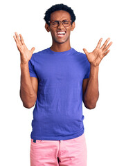 African handsome man wearing casual clothes and glasses celebrating mad and crazy for success with...