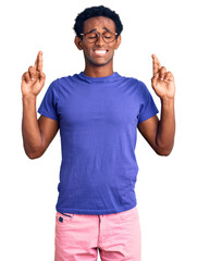 African handsome man wearing casual clothes and glasses gesturing finger crossed smiling with hope and eyes closed. luck and superstitious concept.