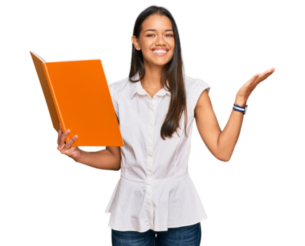 Beautiful hispanic woman reading book celebrating victory with happy smile and winner expression with raised hands