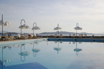 Swimming pool with sun chairs and white parasols around