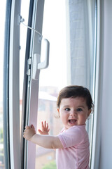 child protective window lock. Little baby girl on windowsill.