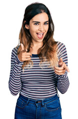 Beautiful hispanic woman wearing casual striped shirt pointing fingers to camera with happy and funny face. good energy and vibes.