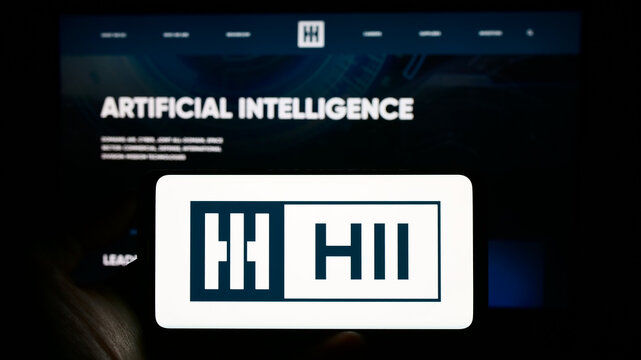 Stuttgart, Germany - 07-02-2023: Person holding cellphone with logo of US shipbuilding company HII Corporate on screen in front of business webpage. Focus on phone display.