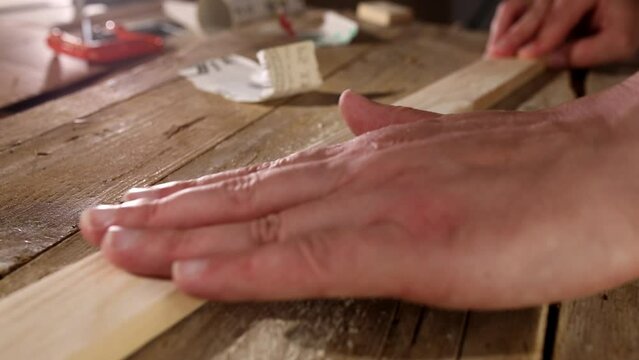 Close-up of a male carpenter's hand checking the smoothness and suitability of a wooden plank after processing. woodworking at home. 