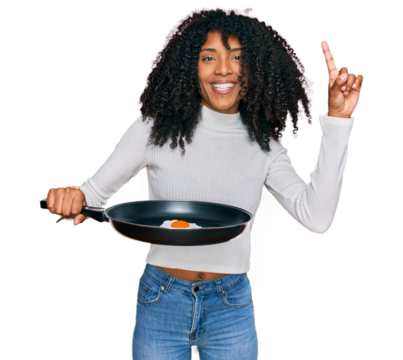 Young african american girl holding skillet with fried egg surprised with an idea or question pointing finger with happy face, number one