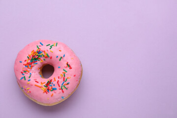 Tasty glazed donut decorated with sprinkles on purple background, top view. Space for text