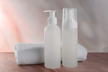 Fototapeta na wymiar Bottles with face cleansing products and towel on beige marble table