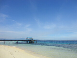 A Pier at Beautiful White Sand Beach Located in North Maluku, Indonesia. Beautiful Scenery of Blue Sky, Ocean and White Sand Beach.