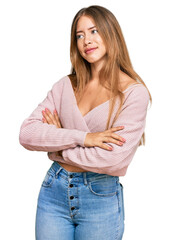 Beautiful blonde woman wearing casual winter pink sweater looking to the side with arms crossed convinced and confident