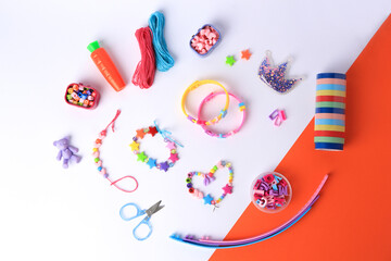 Kid's handmade beaded jewelry and different supplies on color background, flat lay