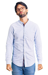 Fototapeta premium Handsome hispanic man wearing business shirt and glasses looking at the camera blowing a kiss on air being lovely and sexy. love expression.