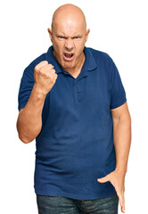 Middle age bald man wearing casual clothes angry and mad raising fist frustrated and furious while shouting with anger. rage and aggressive concept.