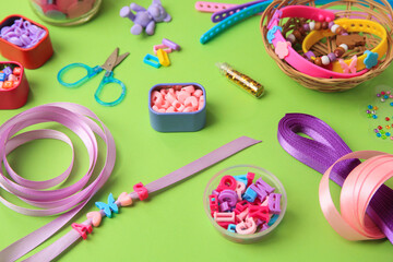 Handmade jewelry kit for children. Colorful beads, ribbons and supplies on green background