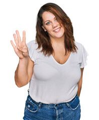 Young plus size woman wearing casual white t shirt showing and pointing up with fingers number four while smiling confident and happy.