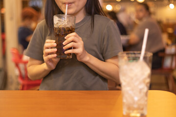 Woman drinking soft drink from the glass in the restaurant. sugary drinks, Unhealthy diet, sweet sugary soft drinks, coke, freshness concept