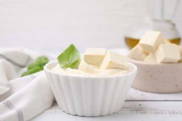 Delicious tofu sauce and basil leaves on white wooden table, closeup
