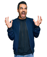 Fototapeta premium Young hispanic man wearing casual clothes crazy and mad shouting and yelling with aggressive expression and arms raised. frustration concept.