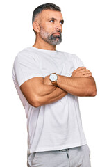 Middle age handsome man wearing casual white tshirt looking to the side with arms crossed convinced and confident