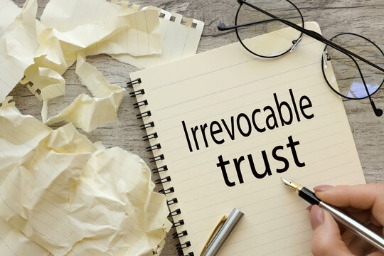 top view of a page with text. woman writes words Irrevocable trust