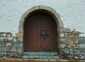Wooden door with iron bolts in stone wall. Copy space