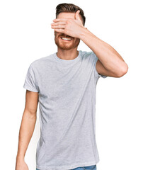 Young redhead man wearing casual grey t shirt smiling and laughing with hand on face covering eyes for surprise. blind concept.