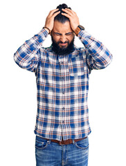 Fototapeta premium Young arab man wearing casual clothes suffering from headache desperate and stressed because pain and migraine. hands on head.
