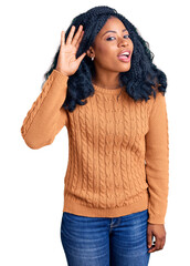 Beautiful african american woman wearing casual  sweater smiling with hand over ear listening an hearing to rumor or gossip. deafness concept.