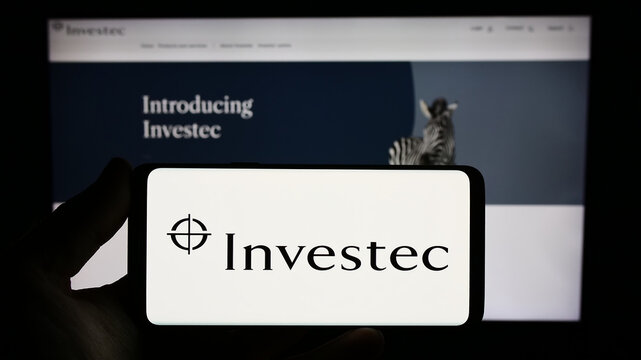 Stuttgart, Germany - 07-04-2023: Person holding smartphone with logo of financial services company Investec Group on screen in front of website. Focus on phone display.