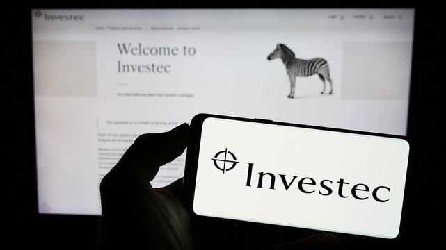 Stuttgart, Germany - 07-04-2023: Person holding mobile phone with logo of financial services company Investec Group on screen in front of web page. Focus on phone display.