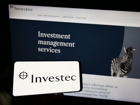 Stuttgart, Germany - 07-04-2023: Person holding cellphone with logo of financial services company Investec Group on screen in front of business webpage. Focus on phone display.