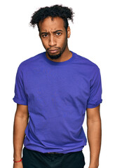 Young african american man with beard wearing casual purple t shirt skeptic and nervous, frowning...