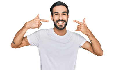 Fototapeta premium Young hispanic man wearing casual white t shirt smiling cheerful showing and pointing with fingers teeth and mouth. dental health concept.