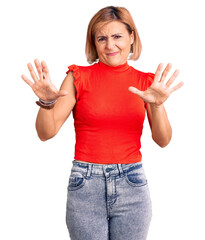 Fototapeta na wymiar Young blonde woman wearing casual clothes afraid and terrified with fear expression stop gesture with hands, shouting in shock. panic concept.